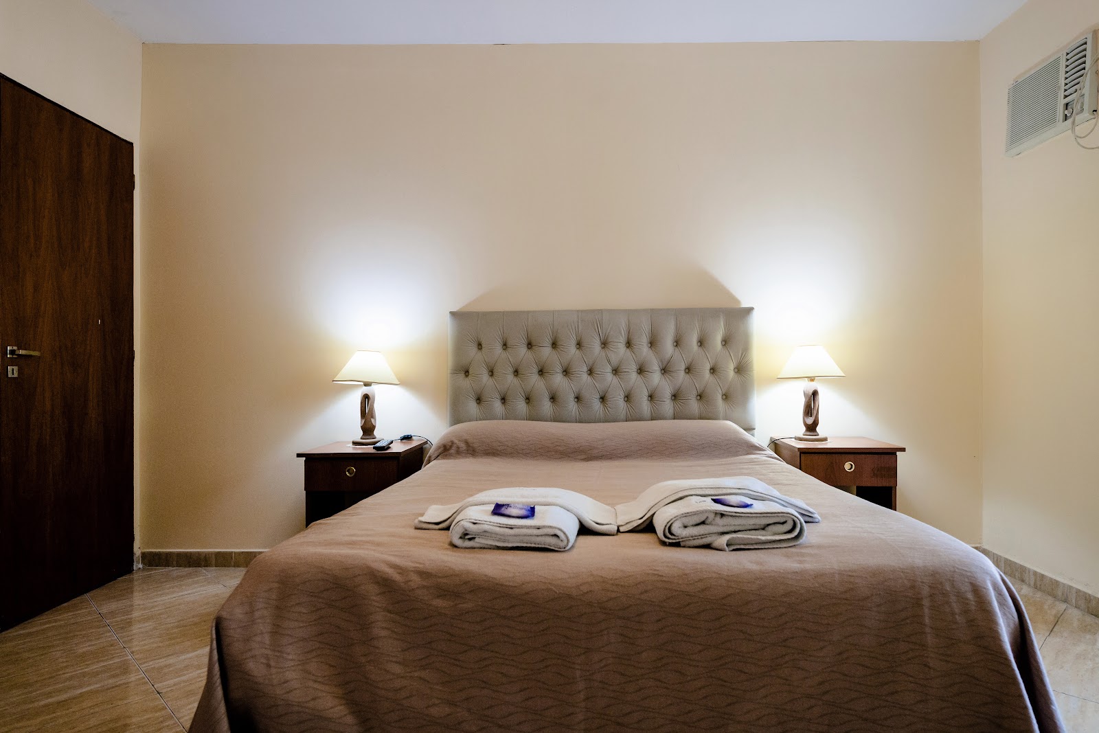 Dormitorio amoblado con cama matrimonial, mesas de luz y aire acondicionado